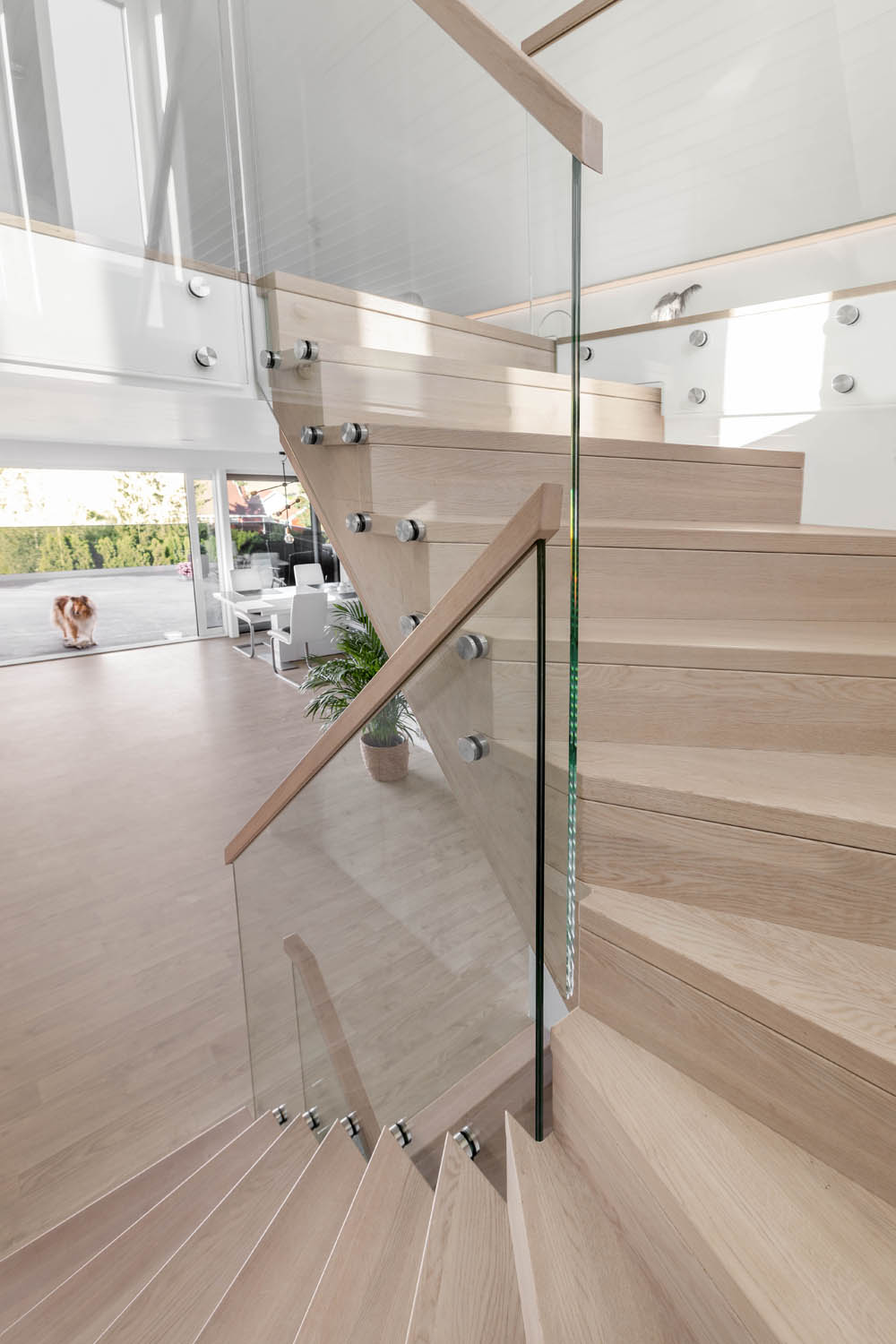 Designtrapp med alle trappens deler i beiset langstav eik, underliggende vange og boltet glassrekkverk